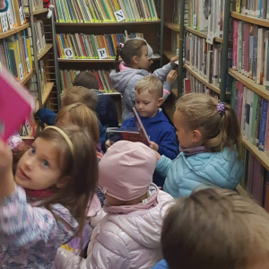 Grupa przedszkolaków pomiędzy regałami z książkami