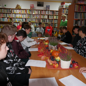 Uczniowie siedzą w czytelni i słuchają wierszy o Jesieni