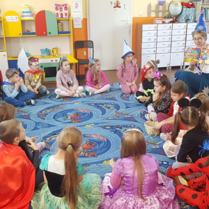 Dzieci siedzą na dywanie i słuchają opowiadania