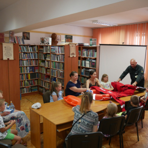 Pan strażak pokazuje uczestnikom spotkania kombinezon strażacki