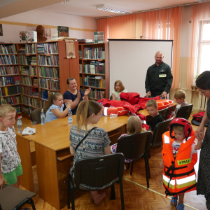 Dziecko w kamizelce strażackiej, w tle uczestnicy spotkania