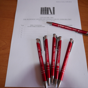 Na stole leży formularz i sześć czerwonych  długopisów