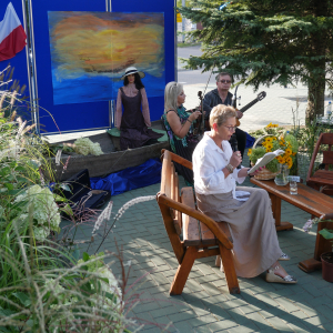 Kobieta siedzi na ławce i czyta W tle kobieta i mężczyzna