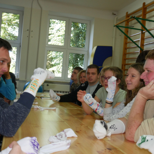 Uczestnicy spotkania  ze skarpetką na dłoniach podczas zajęć lalkarskich