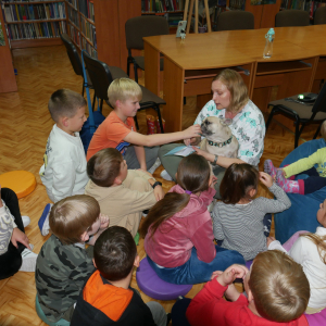 Pani weterynarz trzyma na rękach psa Wokół niej siedzą dzieci