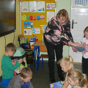 Pani bibliotekarka rozdaje książeczki dzieciom