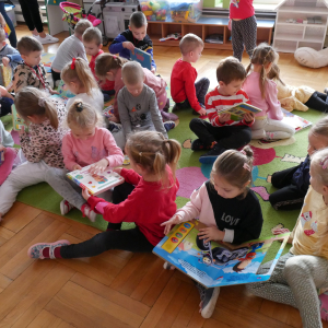 Dzieci siedzą na dywanie i oglądają książki
