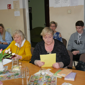 Uczestniczka spotkania czyta wiersz, w tle pozostali uczestnicy spotkania