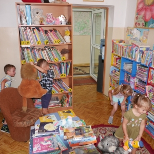 Dwie dziewczynki i dwóch chłopców szukają w bibliotece zwierząt -maskotek Safari.