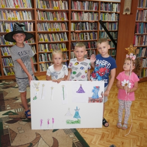 Dwie dziewczynki i trzech chłopców pozują do zdjęcia prezentując swoje prace.