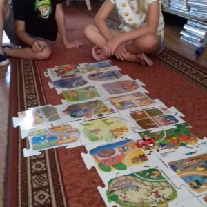 Dziewczynka i chłopiec układają puzzle na dywanie.