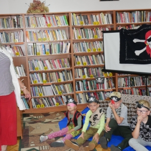 Kobieta i dzieci przebrani za piratów, w tle regały z książkami.