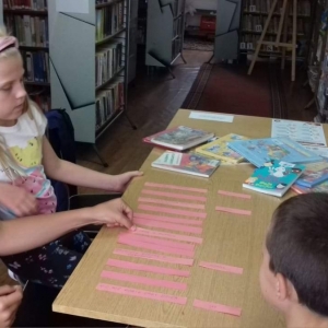 Dzieci układają literackie rozsypanki, w tle regały z książkami.