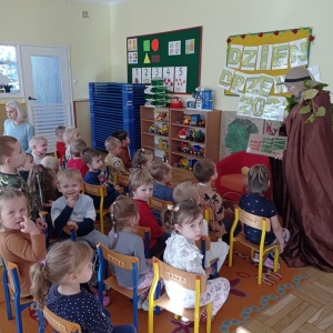 Przedszkolaki siedzą na krzesełkach i słuchają wierszyków