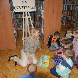 Pani bibliotekarka siedzi z przedszkolakami na dywanie