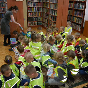 Przedszkolaki siedzą na dywanie i oglądają książeczki