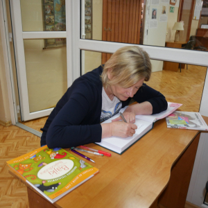 Pani przedszkolanka wpisuje się do Kroniki Biblioteki