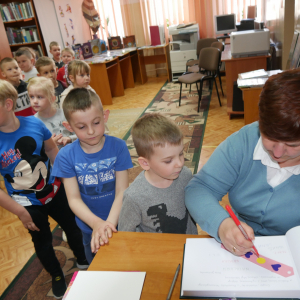 Pani przedszkolanka wpisuje się do Kroniki Biblioteki